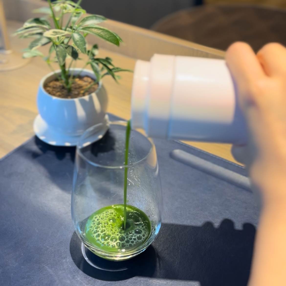 Person pouring well mixed matcha into a glass with Teasy infuser